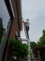Ik sta op de ladder om de dakgoot schoon te maken.